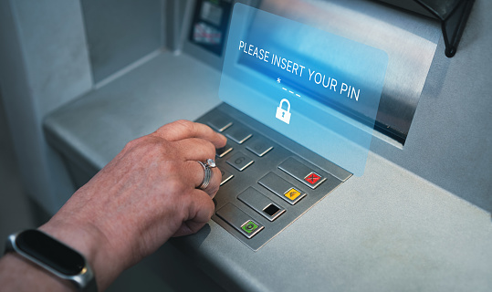 Woman using ATM with holographic interface for security PIN number on the keyboard automatic teller machine.