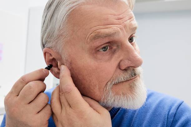istock Grey-haired senior man with hearing impairment using hearing aid. Hearing solutions for deafness people 2050277523