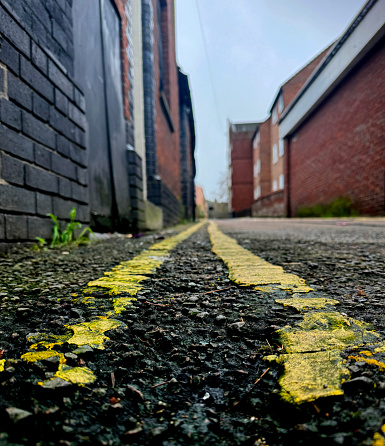 Low angled view of double yellow lines painted in an alley in Norwich