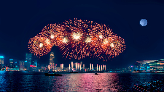 Fireworks display at Victoria Harbor in Hong Kong on a moonlit night.