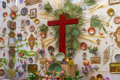Granada, Spain; May 3 - 2024: A decorative wall with a red floral cross, celebrating the traditional May Cross Festival.