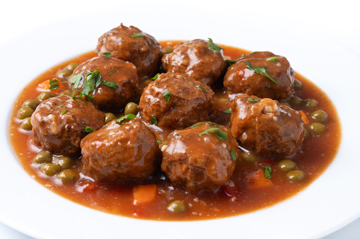 Meatballs, green peas and carrot with tomato sauce isolated on white background