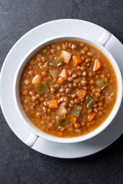 istock Lentil soup with vegetables in bowl on black background 2050340759