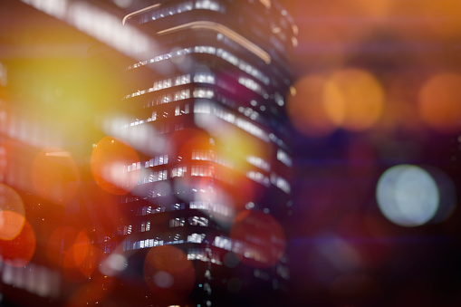 This image captures a softly focused skyscraper at dusk, with the surrounding lights creating a dreamlike bokeh effect, suggesting the vibrant energy of city life enveloped in a bubble of tranquility.
