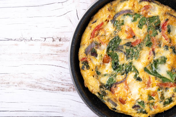istock Italian Frittata made with spinach, tomatoes, onion and peppers isolated on white background 2050347076