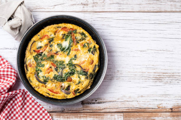istock Italian Frittata made with spinach, tomatoes, onion and peppers isolated on white background 2050347586