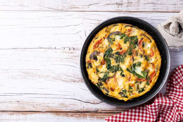 istock Italian Frittata made with spinach, tomatoes, onion and peppers isolated on white background 2050347598