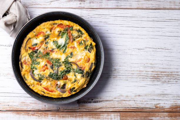 istock Italian Frittata made with spinach, tomatoes, onion and peppers isolated on white background 2050348121