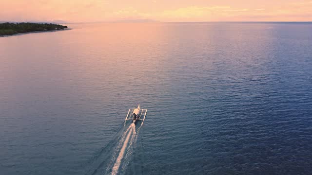 a small fishing boat sails on the sea towards dawn