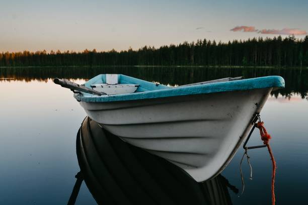 Boat on lake, reflection in water and forest behind, summertime.