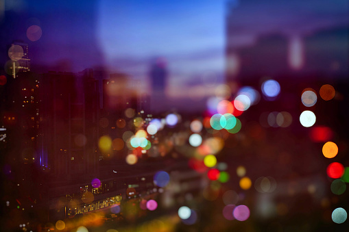 A softly focused cityscape at dusk, where the lights of the city create a colorful array of bokeh, capturing the tranquil mood of the evening.