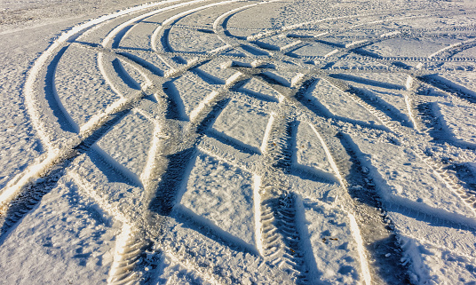 Various winding car tracks on the snow during the day froze