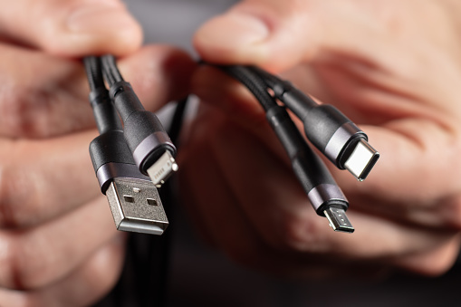 hands holding universal adapter cable from USB connector to micro USB, mini-USB and other connectors.