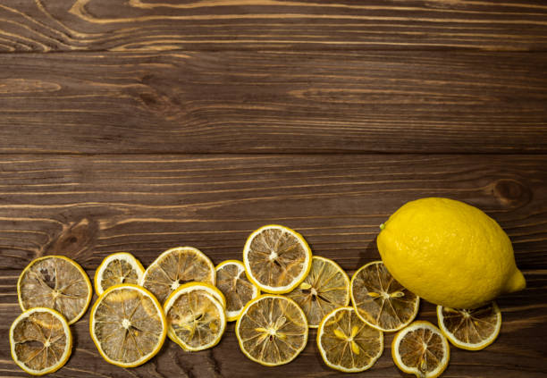 Wooden brown background with fresh lemon and lemon chips
