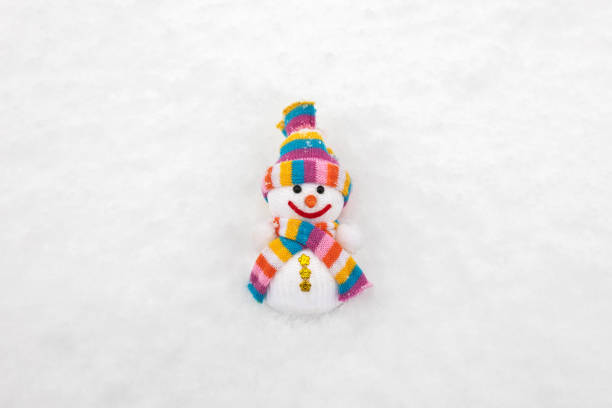 A fabric snowman in a scarf and hat on the snow in winter