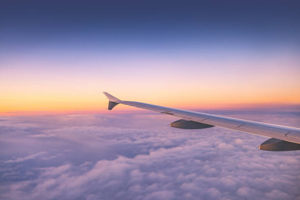 istock Airplane flying over color sky clouds during scenic sunset or sunrise cloudscape, view from plane window of wing turbines and horizon 2050445863