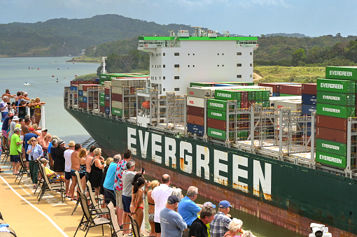 Panama Canal, Panama - 23 January 2024: Passengers on the top deck of a cruise ship looking at a passing container ship