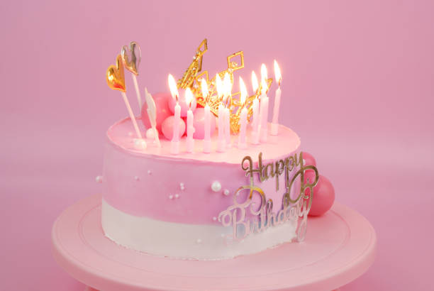 pink birthday cake with gold crown and burning candles - candle heat gold burning stock-fotos und bilder