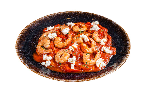 Saganaki Shrimp prawns with tomato and feta cheese on a plate. Dark background. Top view.