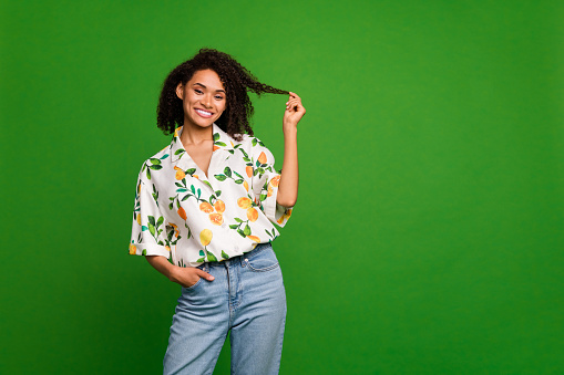 Photo of dreamy flirty lady wear print shirt smiling holding hair curl empty space isolated green color background.