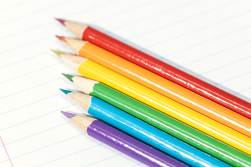 Colored pencils arranged in a formation resembling the pride flag. Copy space