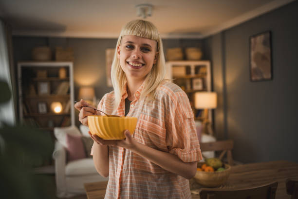 Happy woman at home eating a bowl of cereal for breakfas