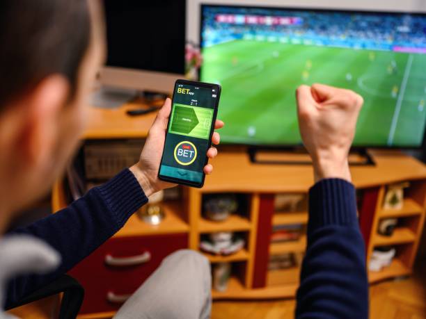 istock Young man using smart phone for sports betting. 2050564004