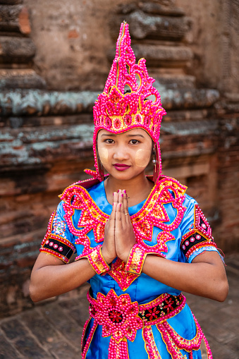 Young Burmese girl with thanaka face paint dancing in the ancient temple of Bagan, Myanmar (Burma)