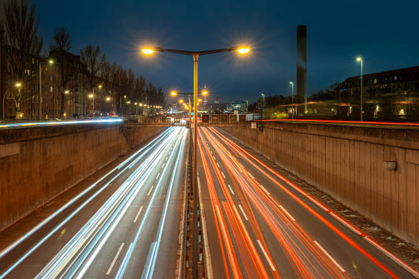 city traffic scene in twilight, long exposure with light trails and motion blur of cars and people, christmas light decoration in downtown district Magdeburg, Germany