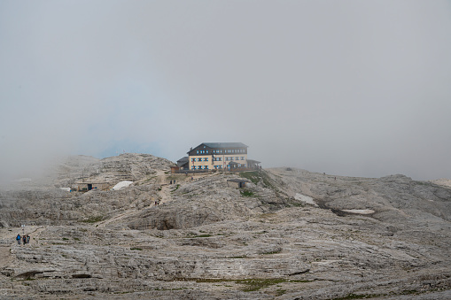 Idyllic landscape in the Alps with traditional mountain chalet and fresh green mountain pastures with blooming flowers at sunset, Mount Dachstein with Mount Bischofsmütze, Sulzenalm