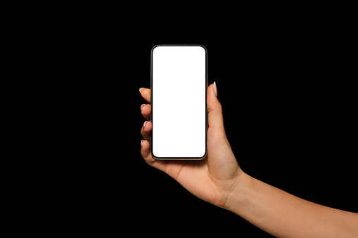 Close-up of a woman's hand holding an iPhone. New modern smartphone, blank screen, black background. high quality photo