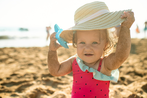 Cute child in straw hat on the beach on summer holidays
