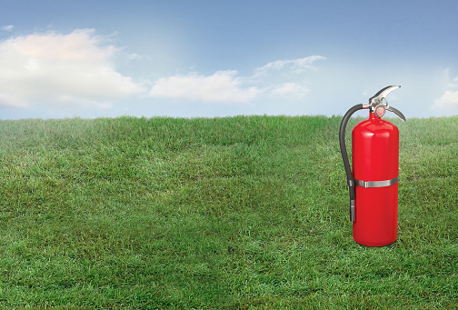 Red fire extinguisher tank on a grass lawn