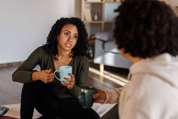istock Girlfriends sitting on the floor, having coffee and chatting 2050617506