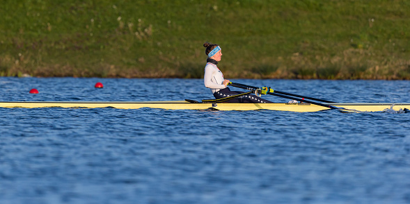 Netherlands, South Holland, Zuidplas, Zevenhuizen, April 19th 2023, early morning side view close-up of a young female rower practising in a yellow scull on the Willem-Alexander Rowing Course in Zevenhuizen near Rotterdam, the venue is suited for international events and was officially opened by Dutch King Willem-Alexander in 2013