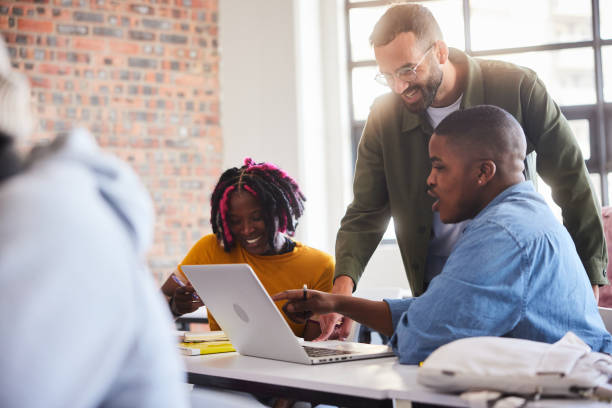 istock Smiling college teacher helping students during a class at school 2050640979