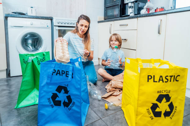 istock Mother is teaching kid how to recycle help the boy aware environmental importance - mom educates son sort garbage into different bins on kitchen. Family sorting garbage at home. Concept of recycling. 2050644848