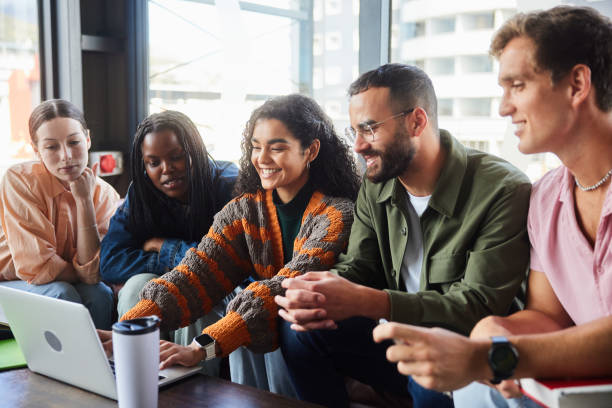 istock Smiling teacher helping students working on a laptop in a school lounge 2050649422