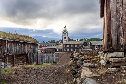 The wooden architecture of Roros frames the path leading to the historic church, standing proud under the expansive Norwegian sky