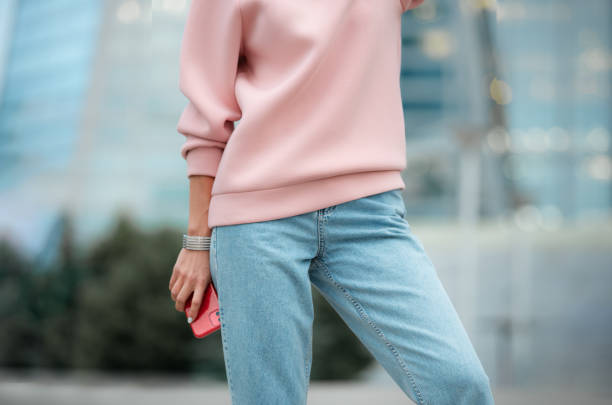 Blue jeans and a pink sweatshirt. A girl in a light pink hoodie and light blue jeans. straight leg pants stock pictures, royalty-free photos & images