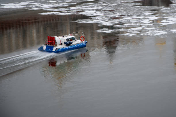 A rescue hovercraft moves along a river covered with broken ice through the reflection of the Kremlin towers on the water. Help and rescue concept.