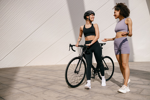 Two sporty female friends talking while standing in city before training. High quality photo