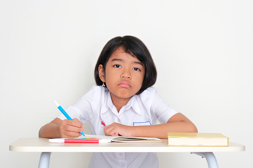 Indonesia kid student sitting on school desk with sad expression