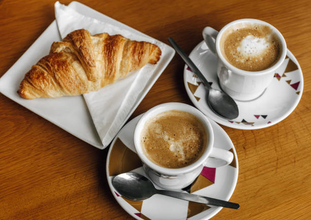 istock Two cups of coffee with milk and a croissant. 2050671614