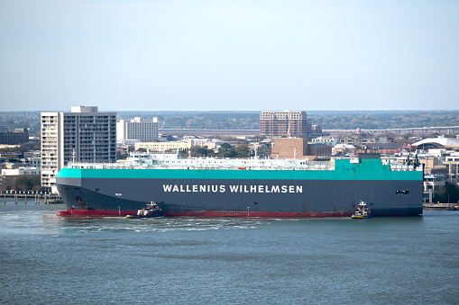 Charleston, SC, USA - February 28, 2024: Two tugboats position the roll-on roll-off vehicles carrier Talia to its mooring site at the Columbus Street Terminal in Charleston Harbor.