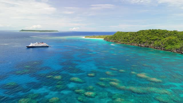 Cinematic drone flight over coral reef with cruise ship anchored in Fiji