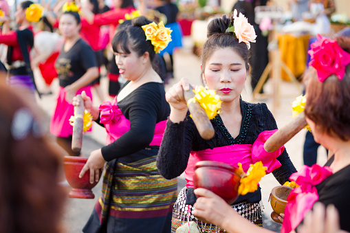 Fun som tam thai dance in Lampang. Thai women are dancing with mortar and pestle and  are performing outdoors in Lampang. Scene is close to and below King Naresuan monument in Lampang during a public festival with food market. Women are dancing for visitors. Dancer women are wearing black shirts traditional skirts and pink scarfs