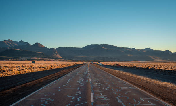 offene autobahn im morgengrauen mit bergiger kulisse - silvara stock-fotos und bilder