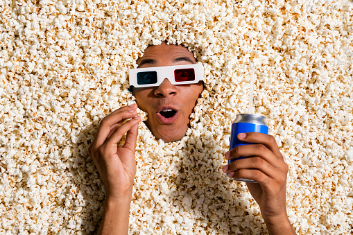 Photo of excited shocked guy spend evening weekend watch tv shows with pop corn lemonade can isolated background.