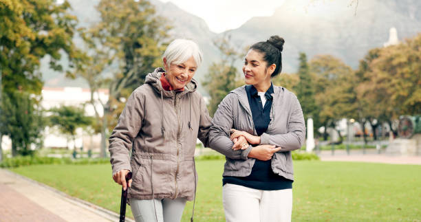 senior woman, walker and nurse outdoor in a park with healthcare for elderly exercise. walking, healthcare professional and female person with peace and physical therapy in a public garden with carer - ouderenzorg stockfoto's en -beelden